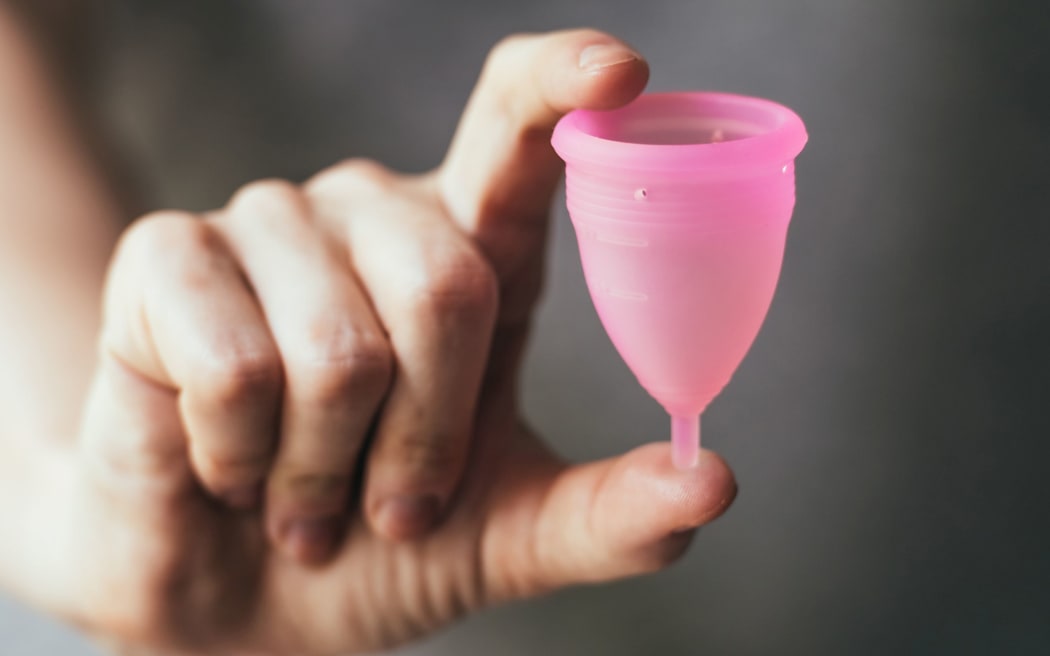 Young woman hand holding menstrual cup. Selective focus and shallow DOF