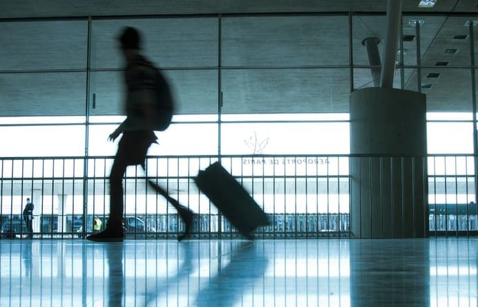 Person at airport with luggage, silhouette.