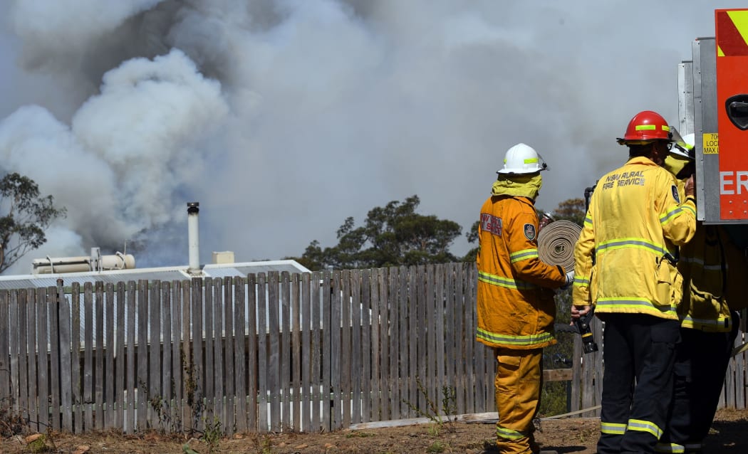 Firefighters secure a house as smoke from bushfires rises in Penrose, in Australia's New South Wales state on January 10, 2020.