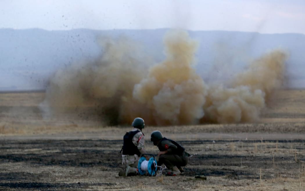Kurdish Peshmerga fighters detonate a land mine laid by IS fighters near Arbil in northern Iraq.