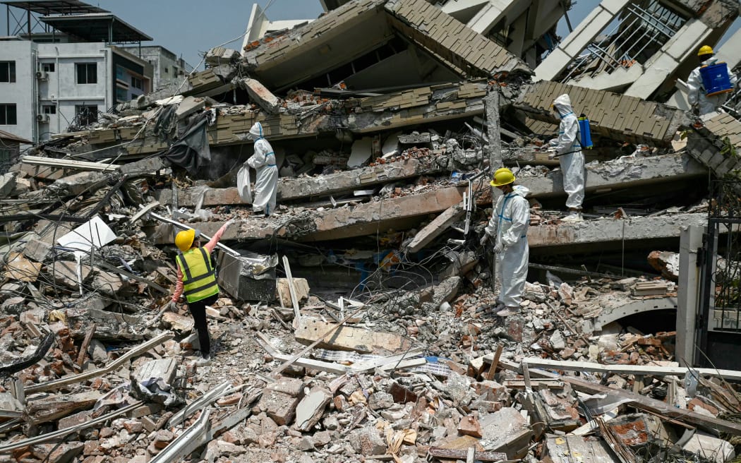 Workers wearing hazmat suit spray disinfectant to sterilise the rubble of a collapsed building in Mandalay on April 2, 2025, five days after a major earthquake struck central Myanmar. Days after a shallow 7.7-magnitude earthquake that killed more than 2,000 people, many people in Myanmar are still sleeping outdoors, either unable to return to ruined homes or afraid of further aftershocks.