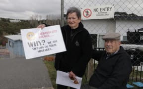 Former Bella Vista residents hold signs expressing their frustration after a compensation for the failed development was rejected.