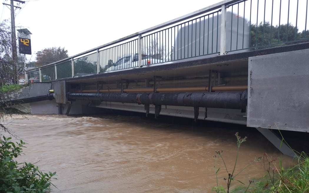 Don Buck Road bridge overflowing in West Auckland.