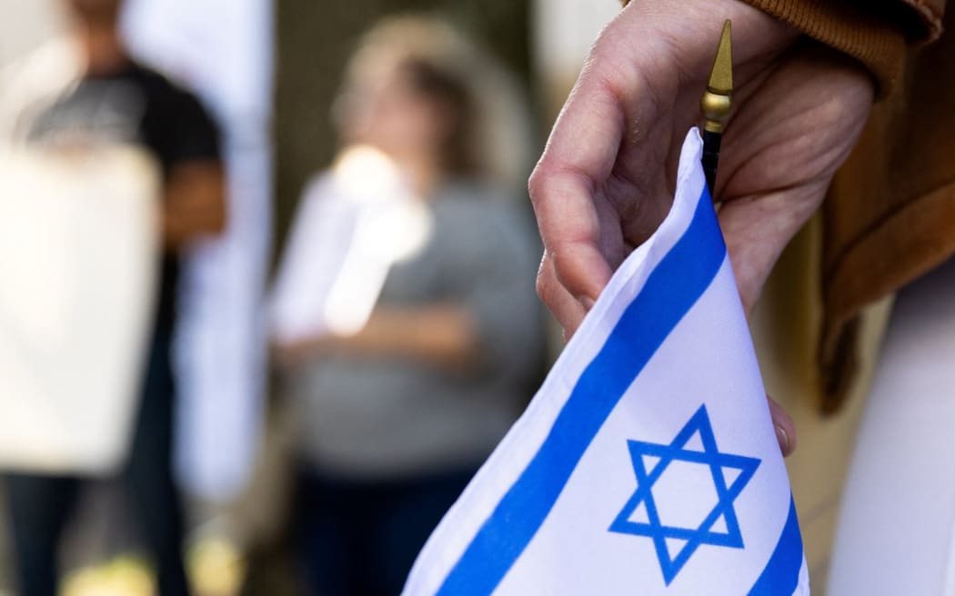 A supporter of Israel holds an Israeli flag in front of the Israeli Embassy in Washington, DC, on October 8, 2023 after the Palestinian militant group Hamas launched an assault on Israel. Israel, reeling from the deadliest attack on its territory in half a century, formally declared war on Hamas Sunday as the conflict's death toll surged close to 1,000 after the Palestinian militant group launched a massive surprise assault from Gaza. (Photo by Julia Nikhinson / AFP)