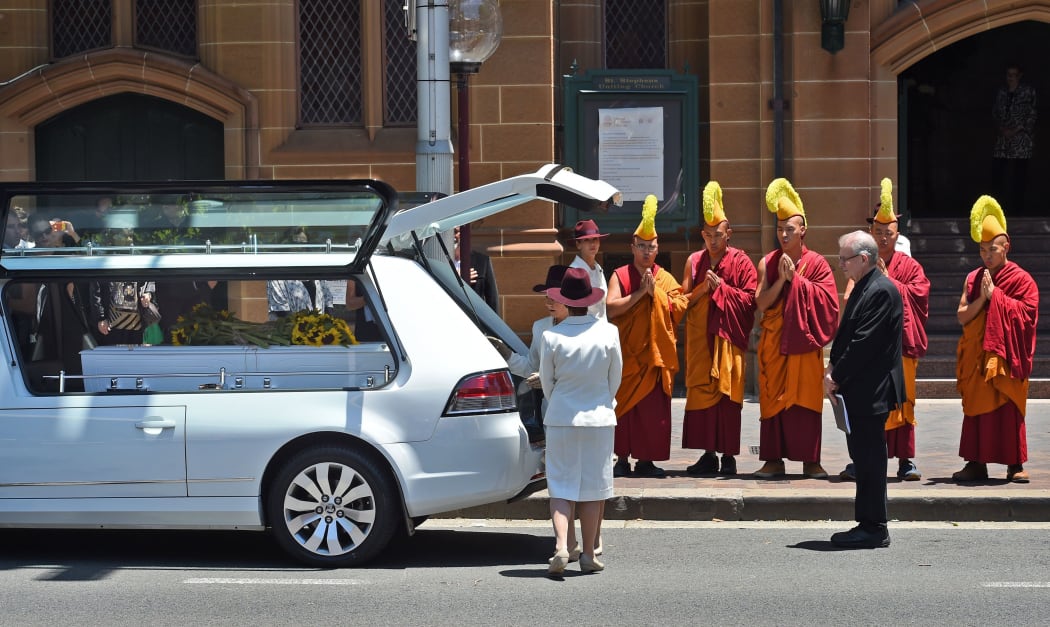 Buddhist monks pray as the coffin of Sydney siege victim Tori Johnson is placed in a hearse after his funeral.