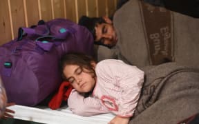 Mohammad from Syria sleeps next to his daughter Aya on a camping bed in refugee accomodation that has been set up in market hall in Kiel, Germany
