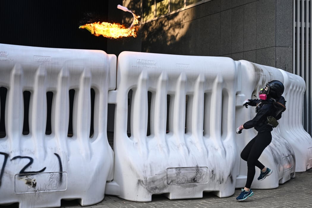A protester throws a molotov cocktail over a barricade outside the government headquarters in Hong Kong on September 15, 2019.
