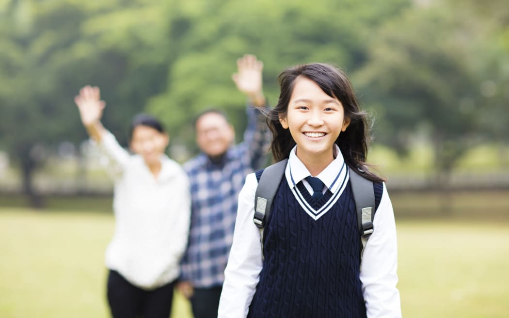 A photo of a cute young student girl with parent in school