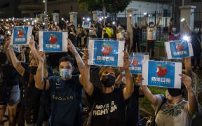 HONG KONG - JUNE 23: Supporters use their their smartphone torches and placards with Apple Daily logos towards the Apple Daily workers outside the headquarters of the Apple Daily newspaper in Hong Kong on June 24, 2021.