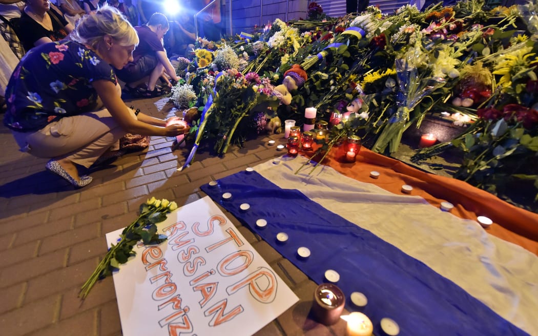 A woman lights a candle in front of the Embassy of the Netherlands in Kiev for those on MH17 in eastern Ukraine.