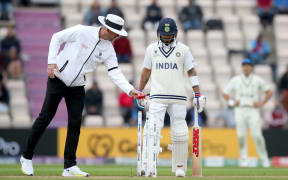 Umpire Michael Gough takes a light reading in front of Virat Kohli the India captain
