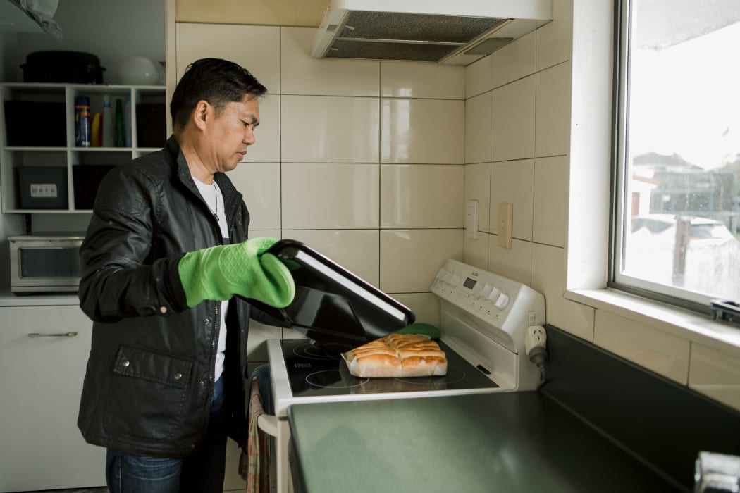 Alfredo takes fresh cheese rolls out of the oven