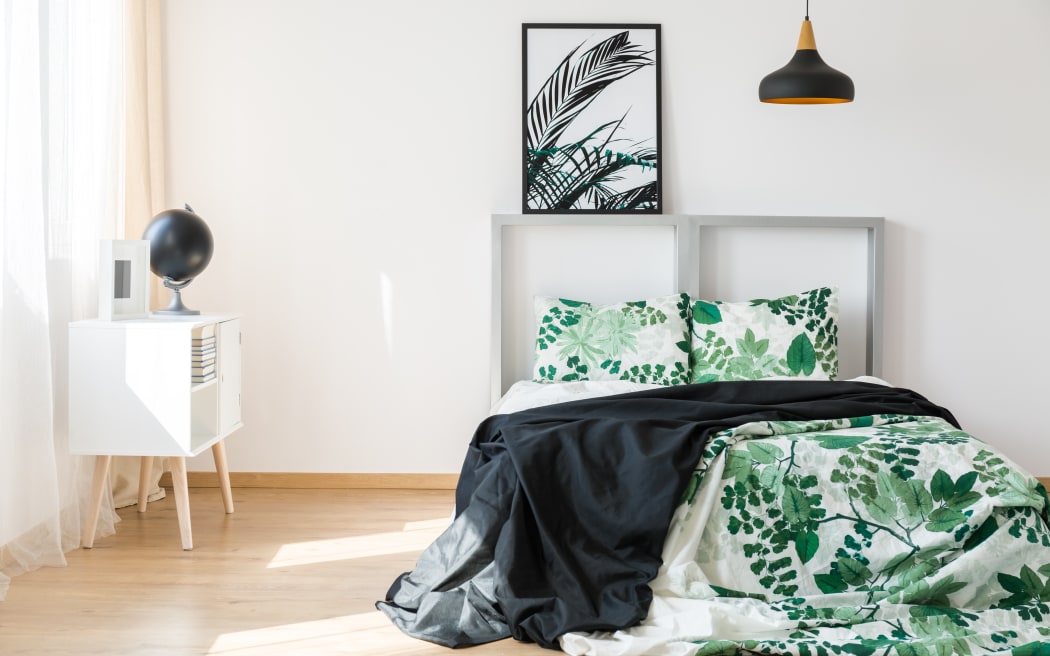 Bed with white and green bedding and metallic bedhead.