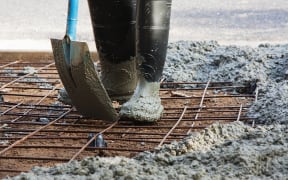 A worker spreads ready-mix concrete over steel mesh (file)