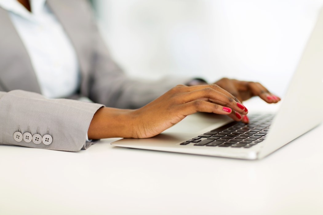 African businesswoman's hands working on laptop.