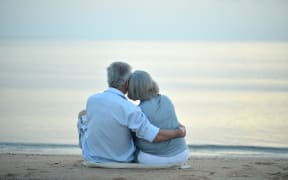 Portrait of happy elderly couple resting on tropical beach