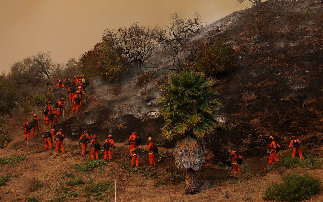 LOS ANGELES, CALIFORNIA - JANUARY 11: Inmate firefighters dig a containment line as they battle the Palisades Fire on January 11, 2025 in Los Angeles, California. The Palisades fire had grown to over 22,000 acres and has destroyed thousands of homes. The fire is currently 11 percent contained.   Justin Sullivan/Getty Images/AFP (Photo by JUSTIN SULLIVAN / GETTY IMAGES NORTH AMERICA / Getty Images via AFP)