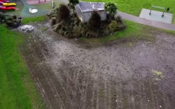 A large muddy patch in the middle of green grass.