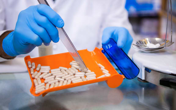 Pharmacist putting pills in container at pharmacy.