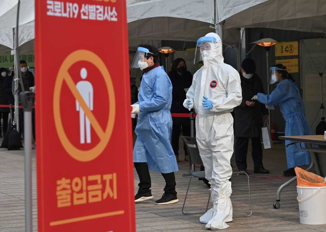 A medical staff member wearing protective gear prepares to test visitors for Covid-19 at a temporary testing station in Seoul on December 23, 2020.