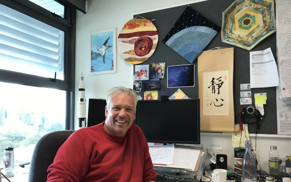 Dr. Nicholas Rattenbury in his office, with a rocket model behind him.