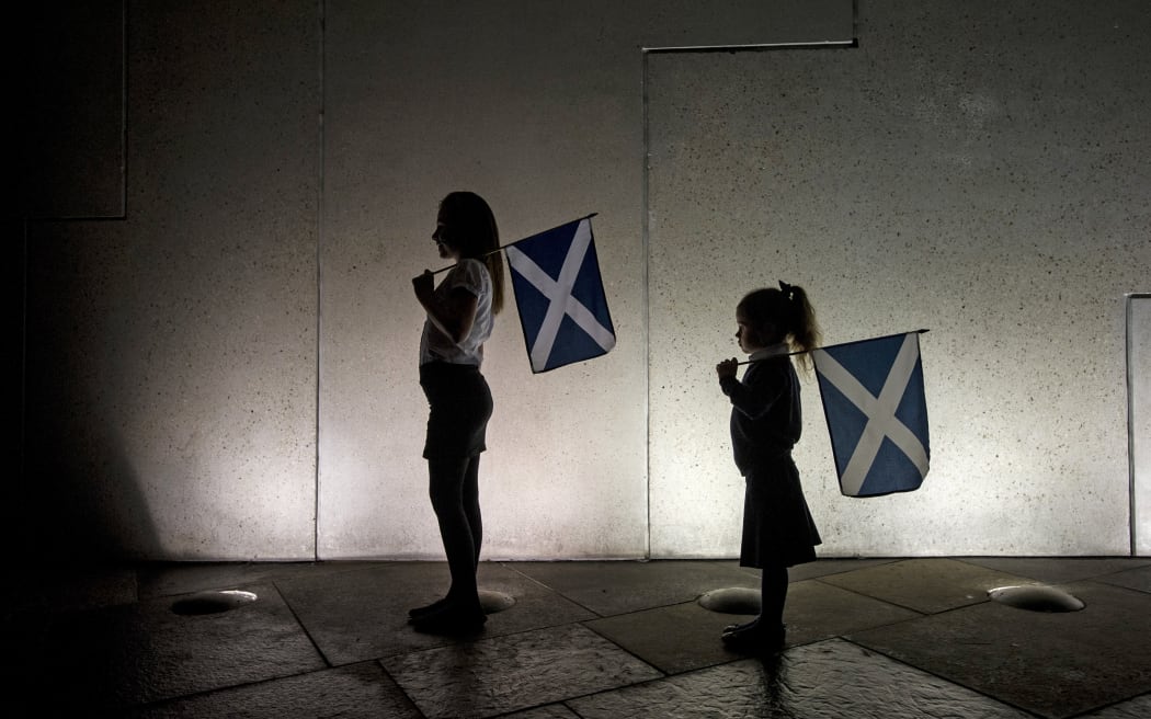Two young girls holding saltires, watch the entertainment outside the Scottish Parliament in Edinburgh on September 18, 2014, during Scotland's independence referendum.