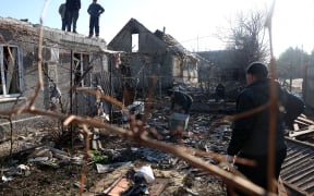 Residents clean debris in a courtyard of a house destroyed as a result of a drone attack in Tairove (alternatively spelled "Tayirove"), Odesa region of Ukraine, on 17 December 2023. (Photo by Anatolii STEPANOV / AFP)