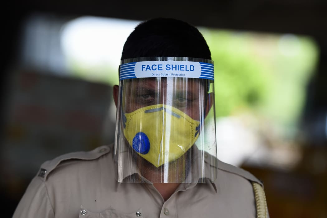 A traffic policeman wearing a face shield checks motorists at a checkpoint during a government-imposed nationwide lockdown in New Delhi on April 13, 2020.