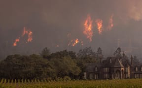 Flames rise behind Ledson Winery on 14 October 2017 in Kenwood, near Santa Rosa, California.