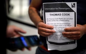 An affected passenger holds an information leaflet after arriving at the closed Thomas Cook check-in desk at the South Terminal of London Gatwick Airport in Crawley, south of London on September 23, 2019.