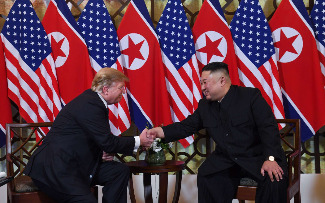 Donald Trump and North Korea's leader Kim Jong Un shake hands in front of a row of their national flags before heading to dinner.