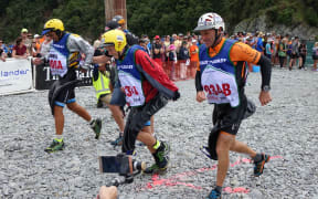 Bryce Adamson, second from right, and Taitama Tukaki, third from right, race to their bikes after completing the kayak section.