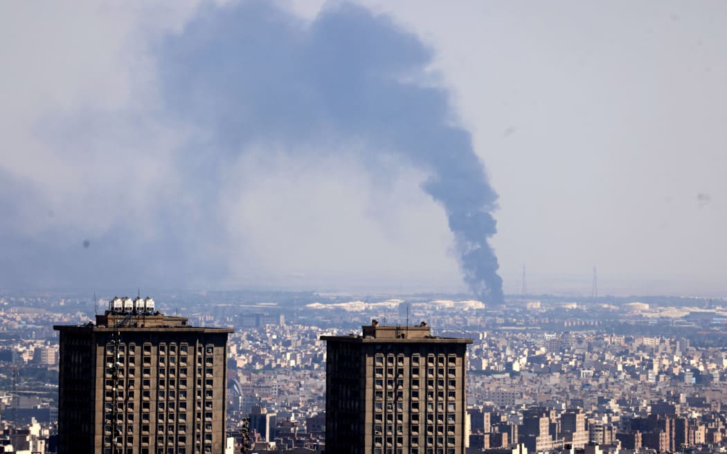 Smoke billows in the distance from an oil refinery following an Israeli strike on the Iranian capital Tehran on June 17, 2025. Israel and Iran exchanged fire again, the fifth day of strikes in their most intense confrontation in history, fuelling fears of a drawn-out conflict that could engulf the Middle East. (Photo by ATTA KENARE / AFP)