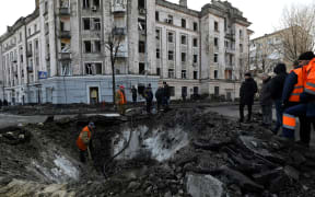 Ukrainian municipal services workers survey and repair the damage following a missile attack in Kyiv, on March 21, 2024, amid the Russian invasion of Ukraine. (Photo by Sergei CHUZAVKOV / AFP)