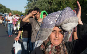 Amina Hmeid - from Deraa in Syria - carries her possessions on her head, as she and hundreds of other refugees and migrants attempt to walk to Austria.