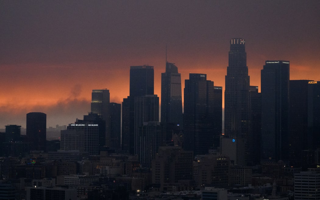 An aerial image shows smoke (L) from the Palisades Fire rising behind the downtown Los Angeles skyline as the city is covered in a haze from wildfires raging around Los Angeles, California on January 8, 2025. - At least five people are now known to have died in wildfires raging around Los Angeles, with more deaths feared, law enforcement said January 8, as terrifying blazes leveled whole streets, torching cars and houses in minutes.
More than 1,000 buildings have burned in multiple wildfires that have erupted around America's second biggest city, forcing tens of thousands of people from their homes. (Photo by Patrick T. Fallon / AFP)