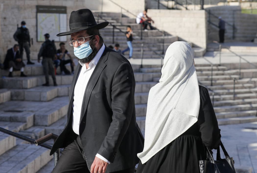 A Palestinian woman and a religious Jewish man walk past each other at the Damascus Gate of the old city of Jerusalem, on May 31, 2020.