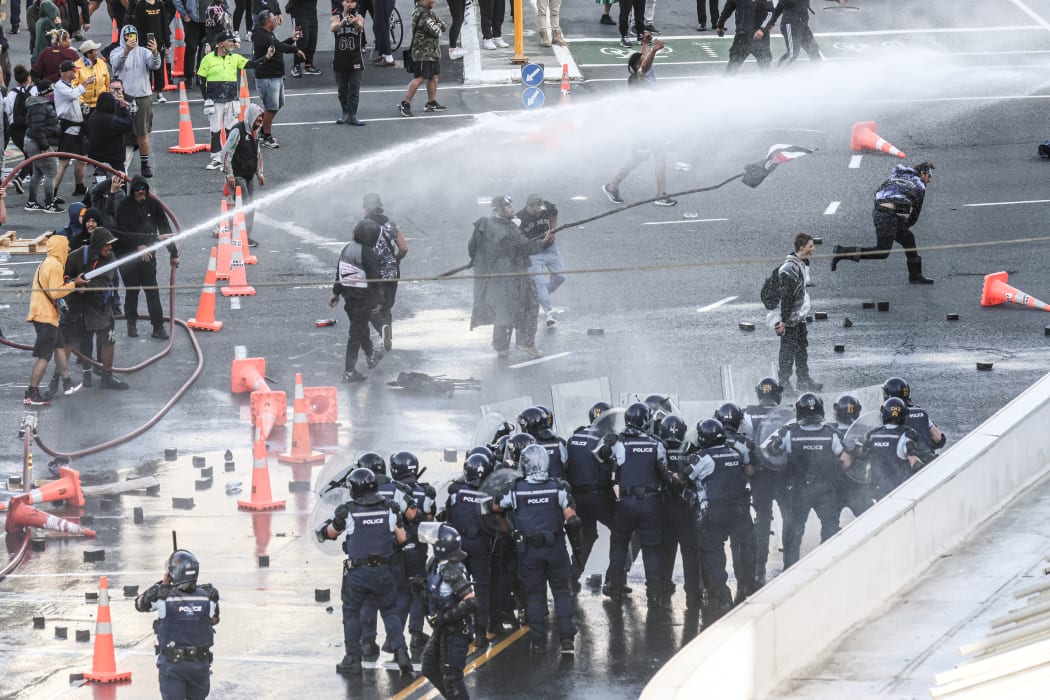 Protestors weld a fire-hose against police.
