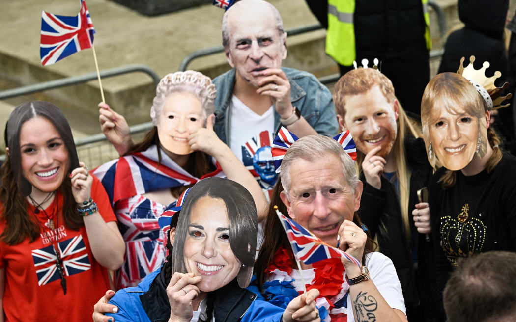 Well-wishers wearing masks of members of the Royal Family wait along the route of the 'King's Procession', a two kilometres stretch from Buckingham Palace to Westminster Abbey, as they wait for Britain's King Charles III and Britain's Camilla, Queen Consort to pass in the Diamond State Coach, in central London, on May 6, 2023 ahead of their coronations. - The set-piece coronation is the first in Britain in 70 years, and only the second in history to be televised. Charles will be the 40th reigning monarch to be crowned at the central London church since King William I in 1066. Outside the UK, he is also king of 14 other Commonwealth countries, including Australia, Canada and New Zealand. Camilla, his second wife, will be crowned queen alongside him and be known as Queen Camilla after the ceremony. (Photo by LOIC VENANCE / AFP)