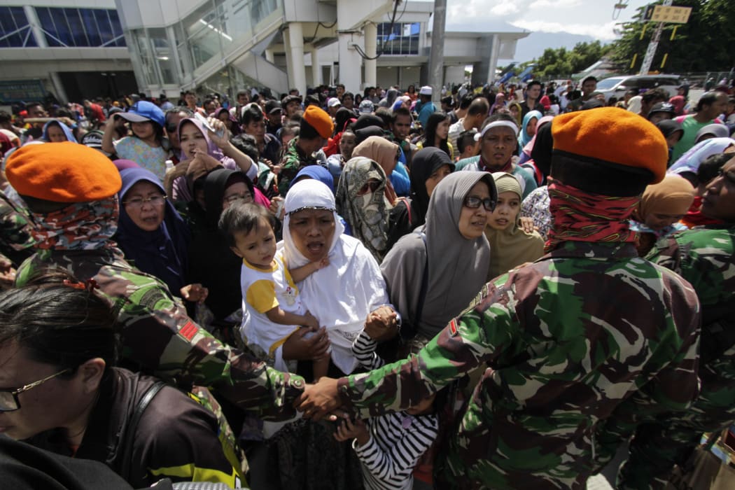Residents queue to board a Hercules aircraft belonging to the Indonesian Air Force, as they are being evacuated after the earthquake and tsunami that hit the city.