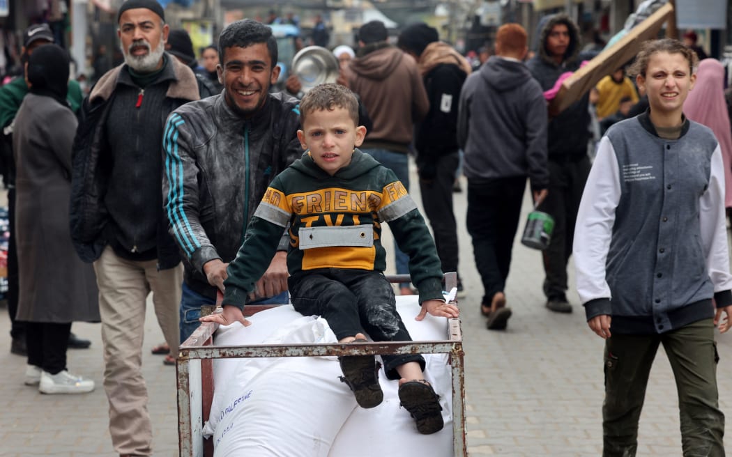 A displaced Palestinian youth pushes a cart loaded with bags of flour they received from the United Nations Relief and Works Agency for Palestine Refugees (UNRWA) in Rafah in the southern Gaza Strip on January 28, 2024, amid ongoing battles between Israel and the Palestinian militant group Hamas. Several key donor countries to the UN agency for Palestinian refugees said they would halt funding following Israeli charges that some UNRWA staff took part in Hamas's October 7 attack. (Photo by AFP)
