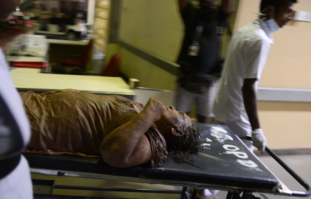 Sri Lankan hospital workers bring in a wounded woman to the main hospital in Colombo on April 14, 2017 - during the country's traditional new year - following a massive rubbish dump fire.