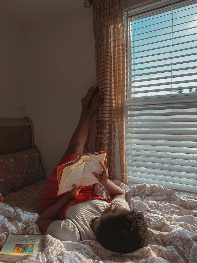 Teenager reading a book in bed.