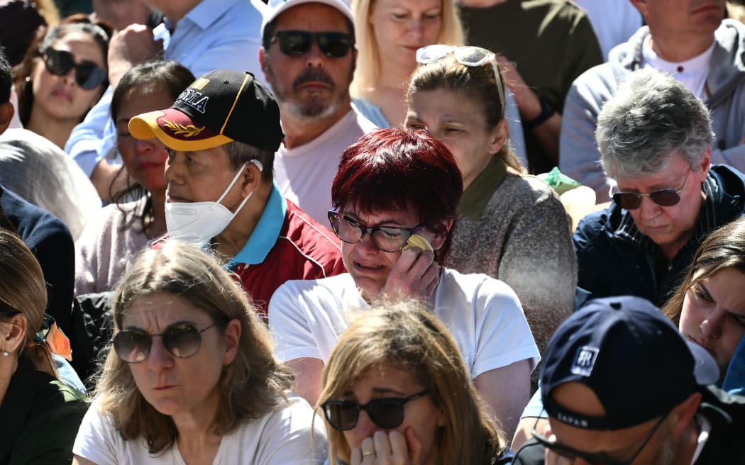 A faithfull reacts as she waits during late Pope Francis' funeral ceremony, in central Rome on April 26, 2025. (Photo by Marco BERTORELLO / AFP)