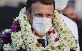 France's President Emmanuel Macron is covered in garlands during a welcoming ceremony upon his arrival at Faa'a international airport for a visit to Tahiti in French Polynesia