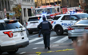 A Metropolitan Police officer walks between patrol cars near a crime scene after a shooting in downtown Washington, DC, on November 26, 2025. Two members of the National Guard were shot Wednesday just blocks from the White House, according to officials, as a spokesperson for Donald Trump said the president has been briefed on the "tragic situation." Police said they had detained a suspect. (Photo by Drew ANGERER / AFP)