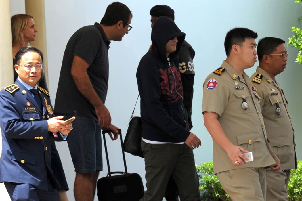 A refugee (3rd R) held under Australian custody in the Central Pacific island of Nauru is escorted by Cambodian police following his arrival at the Phnom Penh International airport on June 4, 2015.