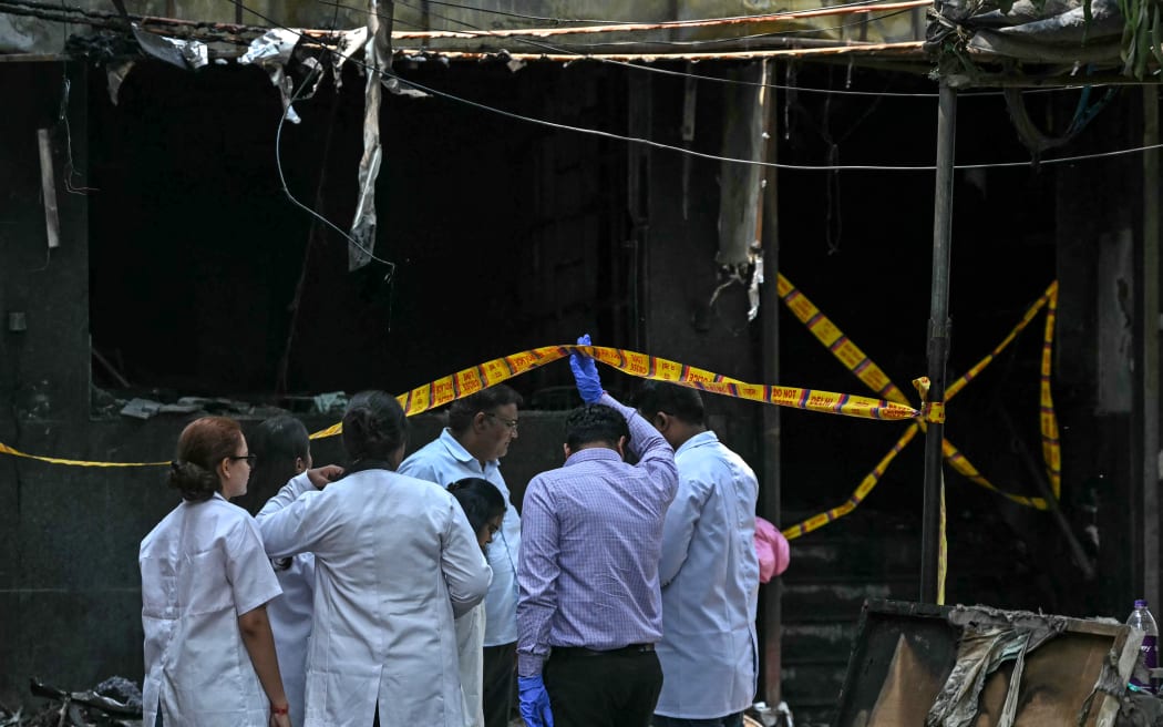 Forensics team members inspect the site following a fire that broke out at a hotel in New Delhi on June 3, 2026. At least 21 people were killed when a fire ripped through a hotel in New Delhi on June 3, police said, in one of the deadliest blazes in the Indian capital in recent years. (Photo by Arun SANKAR / AFP)