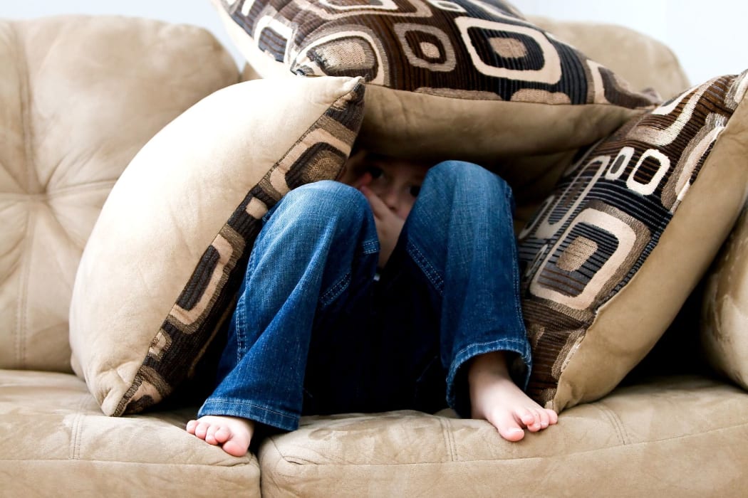 Boy hiding in cushions