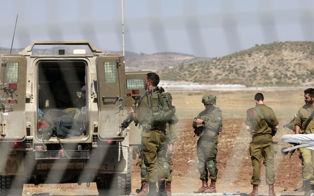 Israeli forces stand during the evacuation of a wounded soldier in the Israeli town of Muqeibila, north of the occupied West Bank, on July 3, 2023. Israel has stepped up operations in the northern West Bank, home to Jenin city and its adjacent refugee camp, a stronghold of Palestinian armed groups where there has been a spate of attacks on Israelis as well as attacks by Jewish settlers on Palestinian communities. (Photo by Menahem KAHANA / AFP)